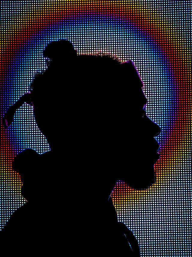 Human with a screen displaying colourful lighting in the background