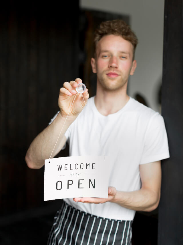A Steward Placing the 'we are open' sign on the shop door