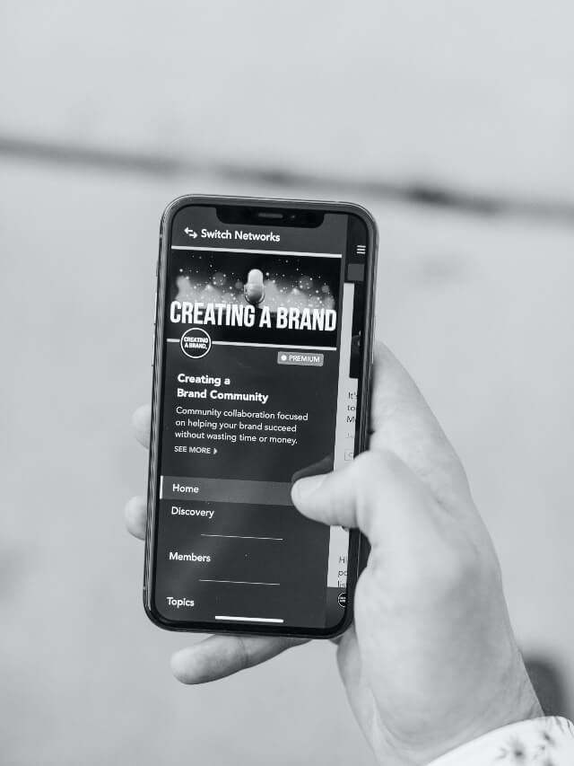 A person holding a mobile device displaying 'creating a brand' on the screen.