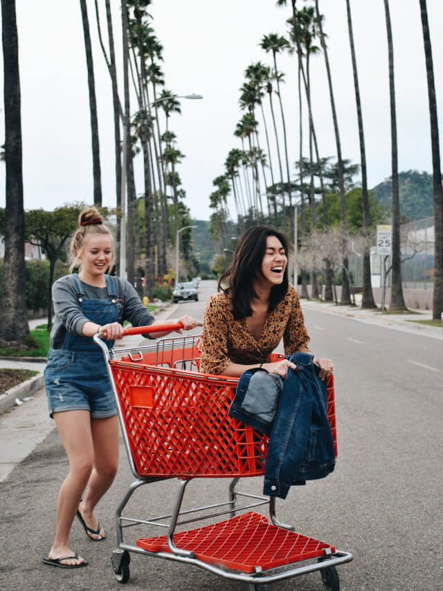 A lady dragging a cart with her friend sitting in it